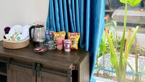 Een tafel met lekkernijen, een mandje en een plant bij een raam met blauwe gordijnen.