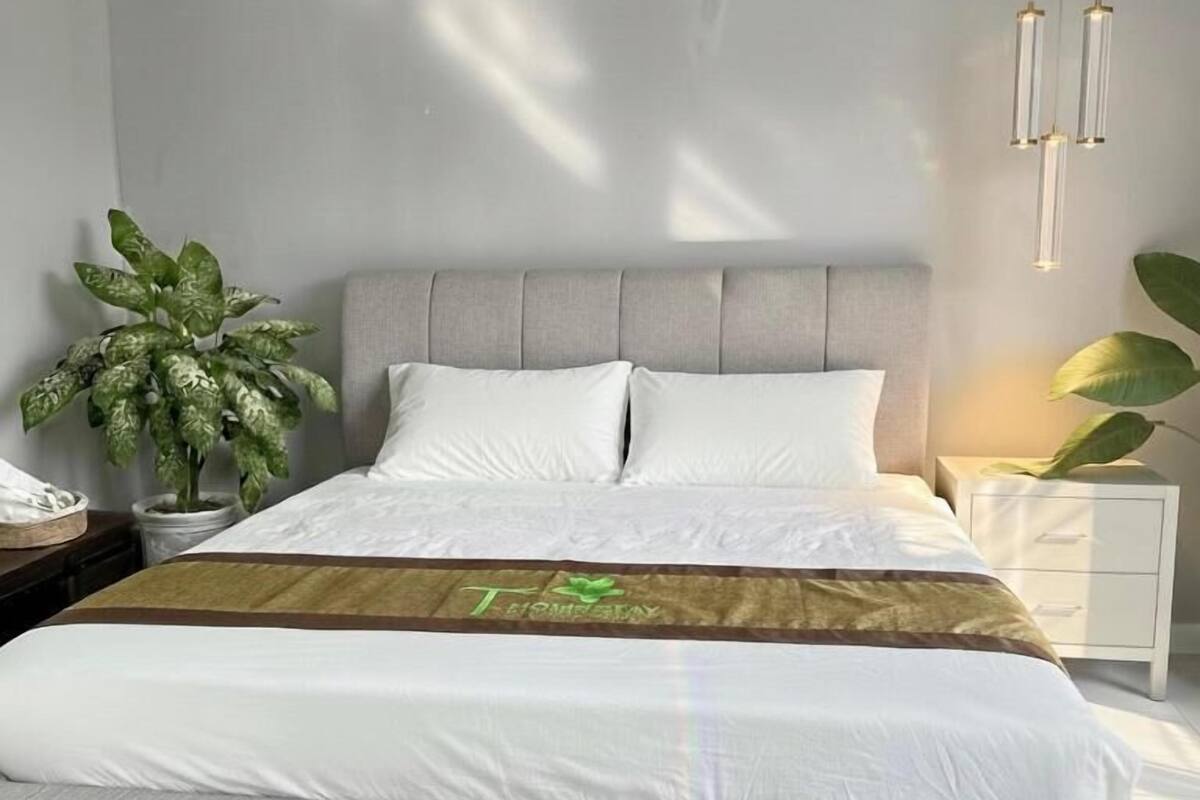 Une chambre moderne avec un lit, des tables de chevet, une plante en pot et un luminaire suspendu.