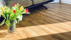 Un salon moderne avec un canapé, un téléviseur à écran plat fixé au mur et un plancher en bois.