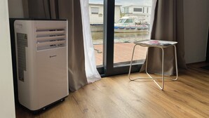 Une pièce avec une grande fenêtre, un radiateur et une petite table sur laquelle se trouve un magazine.