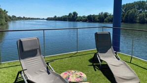 Deux fauteuils confortables sur une terrasse avec vue sur la rivière.