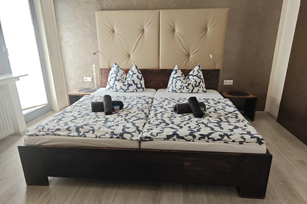 A bed with a patterned bedspread, two pillows, and rolled towels.