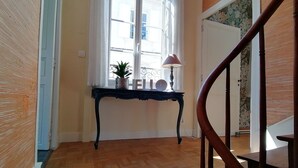 Un suelo de madera, una mesa negra con una lámpara y una ventana con vistas.