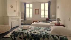 Una habitación de hotel con dos camas, un escritorio, un radiador y una ventana con cortinas.