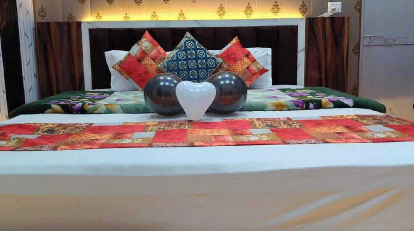 A bed with a patterned bedspread, decorative pillows, and a heart-shaped object on the bed.