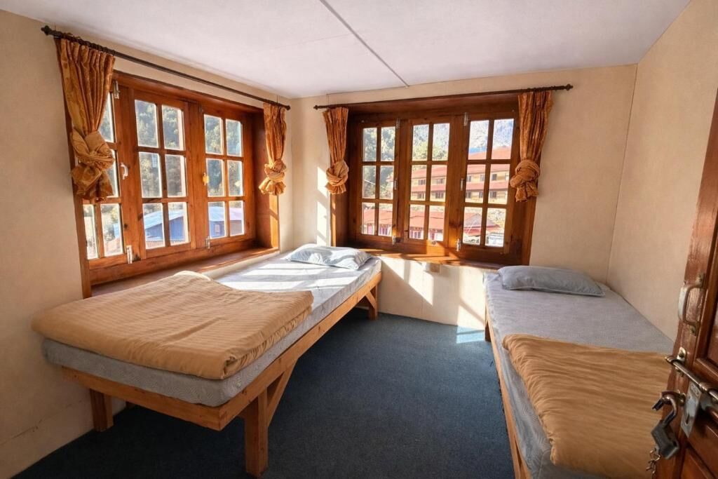 Une chambre avec deux lits, des fenêtres en bois et des rideaux.