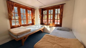 A room with two beds, a window, and a small table.