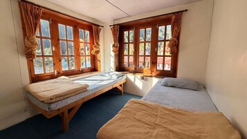 Una habitación con dos camas, una ventana y una mesita.