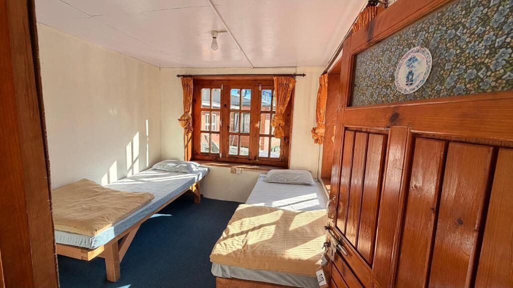 Une petite pièce avec deux lits simples, une fenêtre avec des rideaux et un meuble en bois.