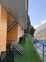 Un edificio de madera con balcón, asientos al aire libre y una escalera.