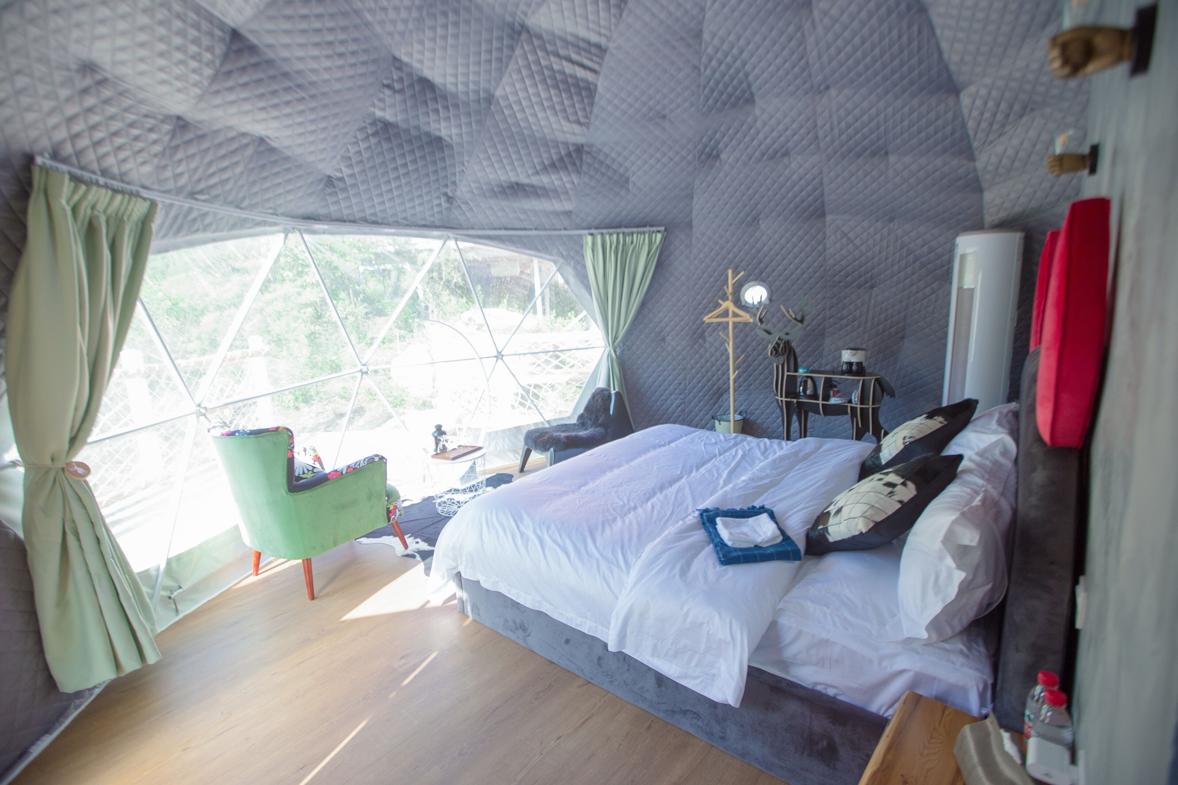 A room with a bed, a chair, a table, and a window with curtains.