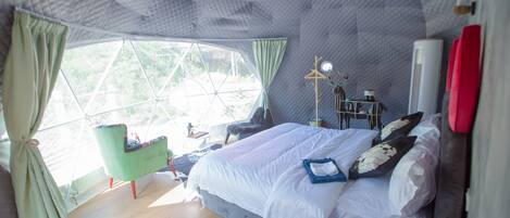 A room with a bed, a chair, a table, and a window with curtains.