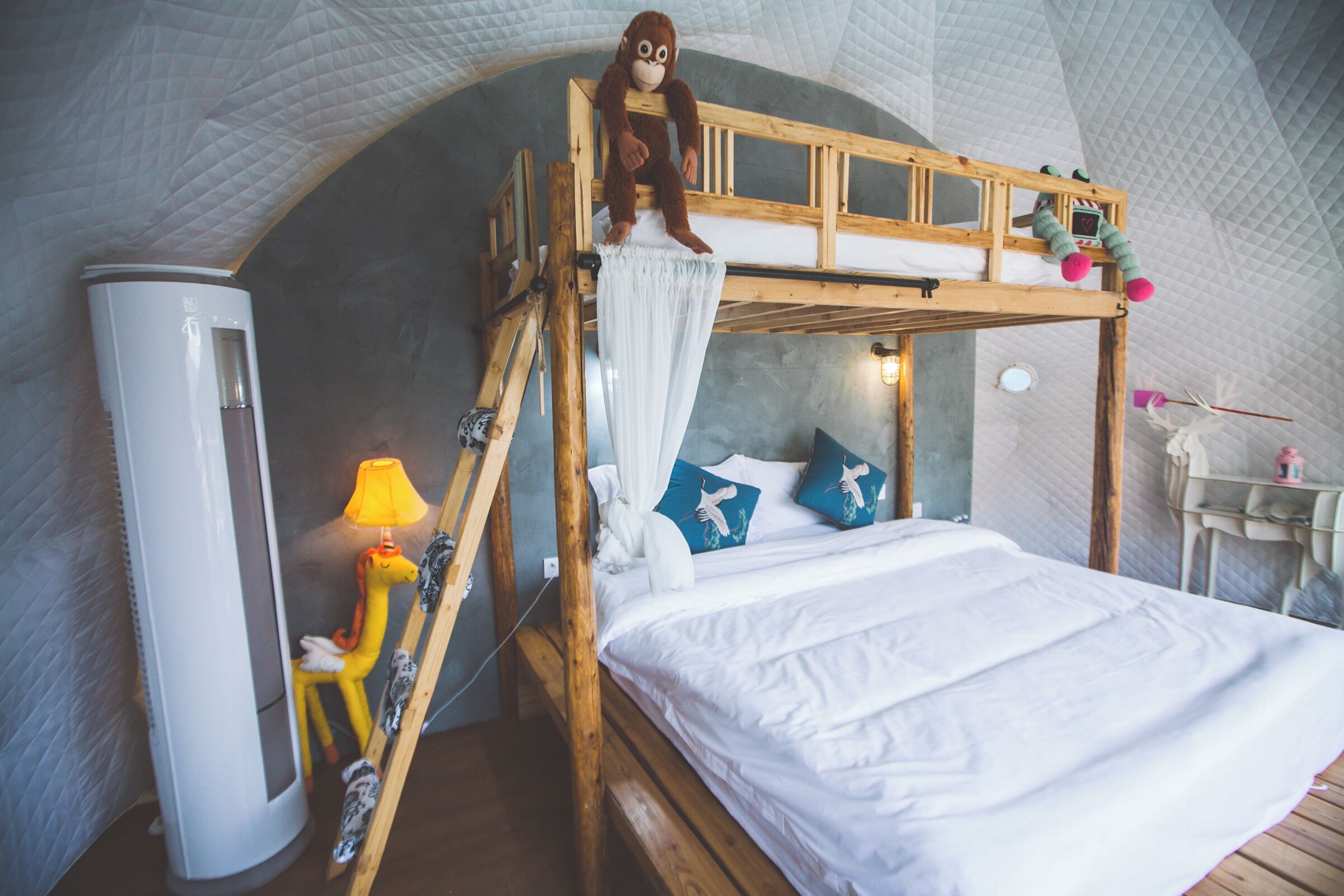 A bunk bed with a monkey plush toy, a lamp, and a small table with a toy.