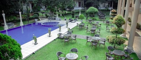 A courtyard with a swimming pool, outdoor seating, and greenery.