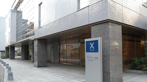 Un edificio moderno con una entrada destacada marcada por un letrero azul que muestra una 'X' y la palabra 'WAVE'.