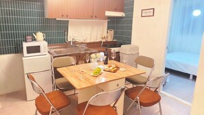 Une cuisine de taille réduite comprenant une table à manger, des chaises et un four à micro-ondes.