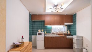 Une cuisine compacte avec des meubles en bois, un four à micro-ondes, un évier et un petit réfrigérateur.