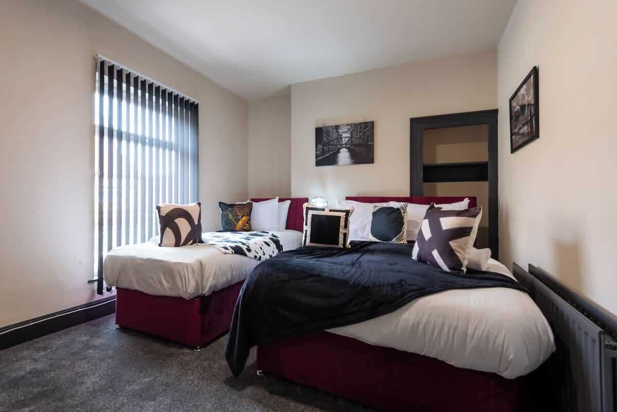 Un dormitorio con dos camas, una ventana con persianas y un cuadro en la pared.