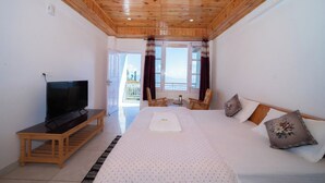 Una habitación con cama, televisor, techo de madera y vista al exterior.