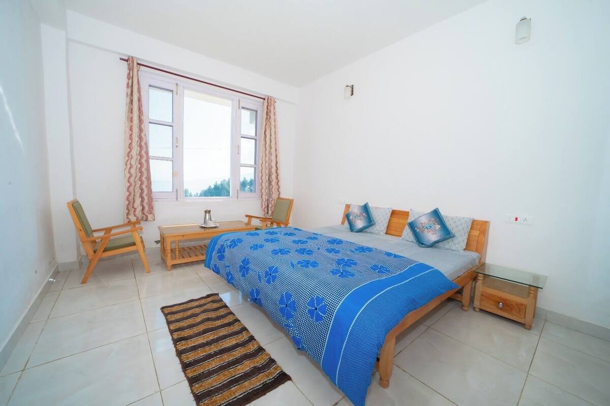 A bedroom with a bed, a chair, a table, and a window.