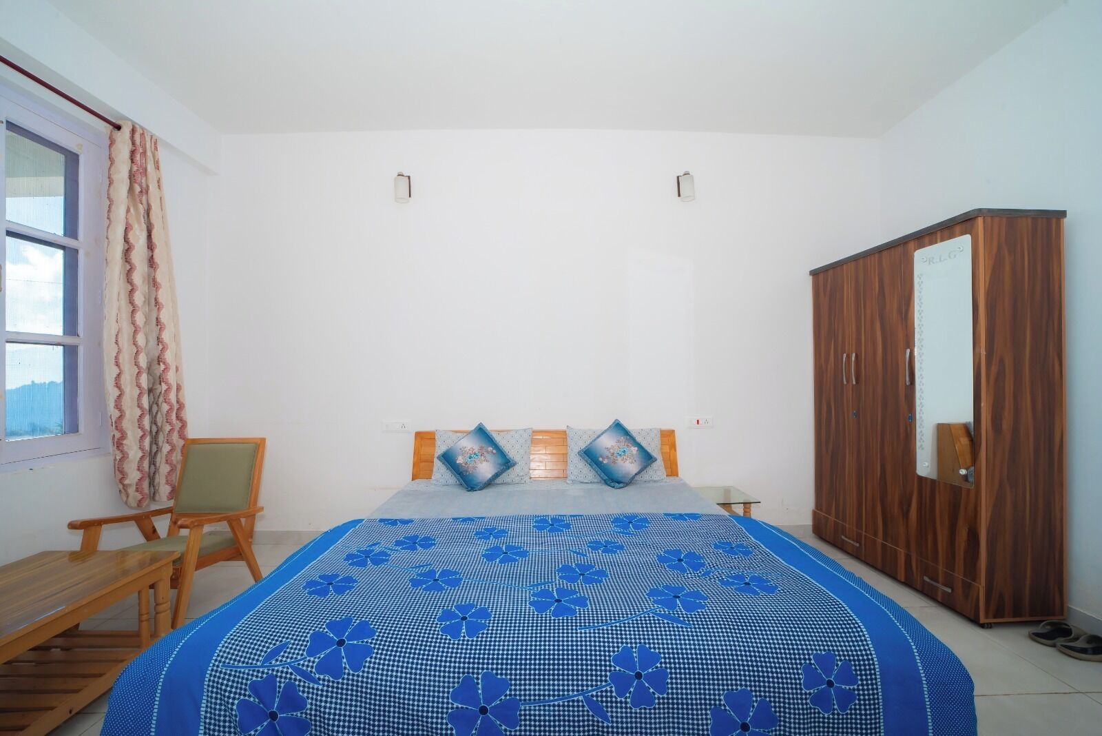 A bedroom with a bed, wooden wardrobe, and a chair.