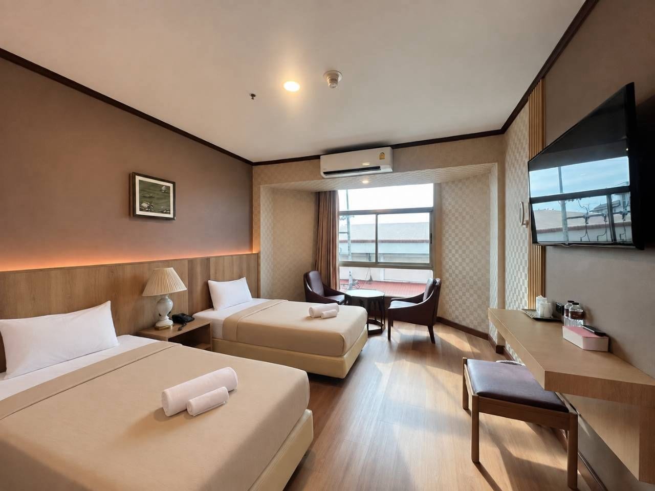 Ein Hotelzimmer mit zwei Betten, einem Schreibtisch, einem Sessel, einem Fernseher und einem Fenster mit Blick.