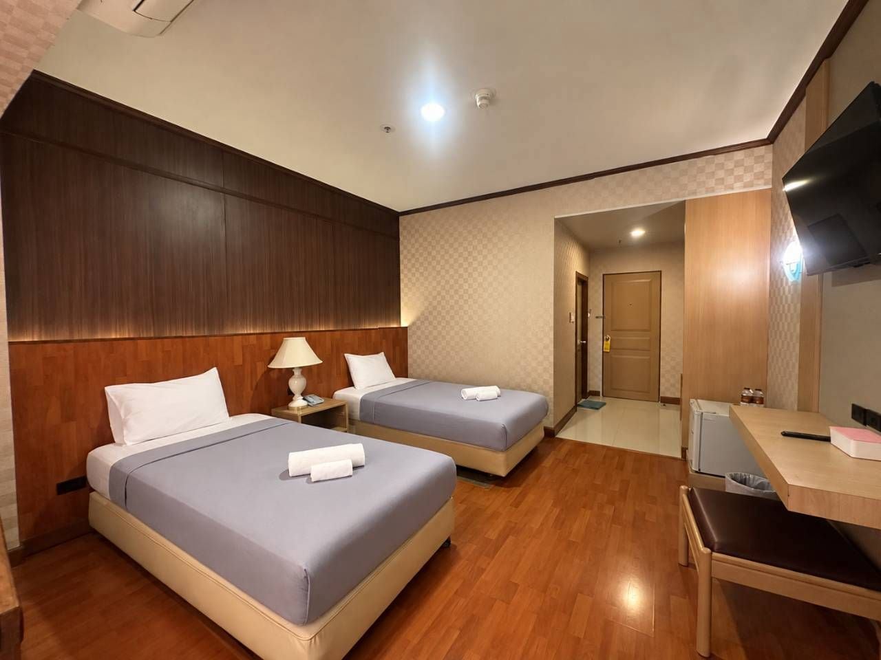 Une chambre d’hôtel avec deux lits, un bureau, une télévision et une porte donnant sur une salle de bain.
