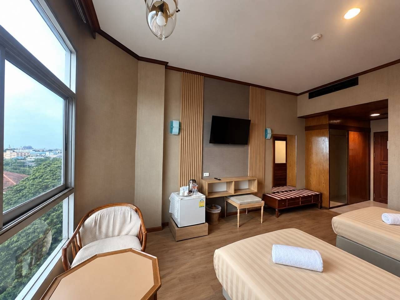 A hotel room with a bed, a desk, a chair, a television, and a view of the city.