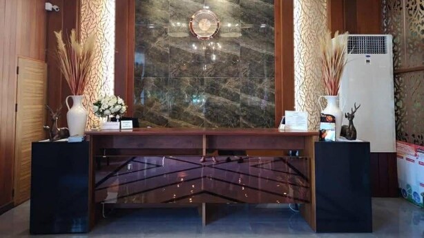 A reception area with a marble wall, two pendant lights, a reception desk, and decorative items. - Lertthanee Hotel (Suphan Buri)