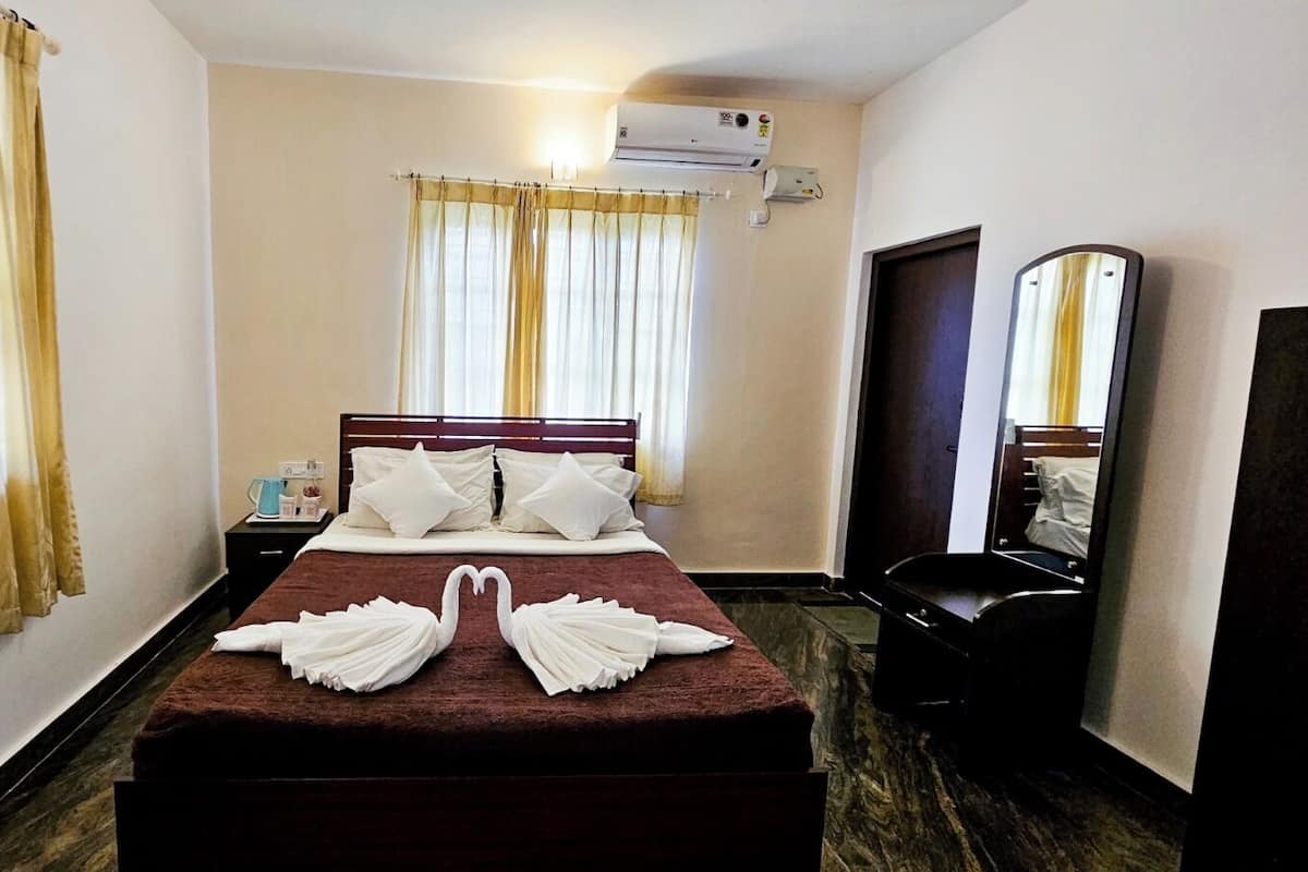 Ein Hotelzimmer mit Bett, Vorhängen, Klimaanlage, Spiegel und Nachttisch.