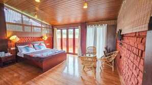 Une pièce comprenant un lit, une table, des chaises et offrant une vue sur l’extérieur grâce à de grandes fenêtres.