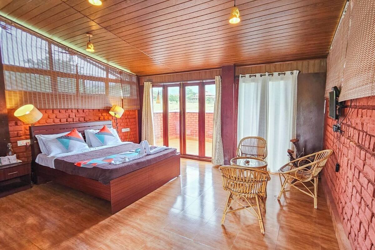 Ein Zimmer mit einem Bett, einem Tisch, Stühlen und Blick durch große Fenster.