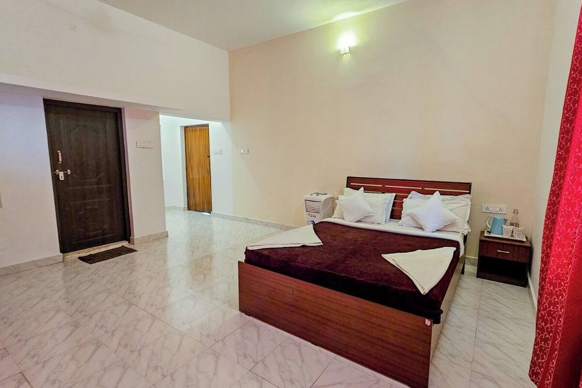 Ein Hotelzimmer mit einem Bett, einem Nachttisch und einer Tür zu einem weiteren Raum.