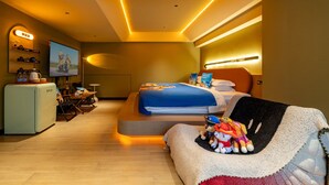 Un dormitorio moderno con cama, escritorio, silla, sofá, televisor y refrigerador.