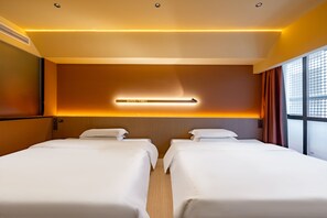 Une chambre d’hôtel avec deux lits, une lampe fixée au mur et une fenêtre avec des rideaux.