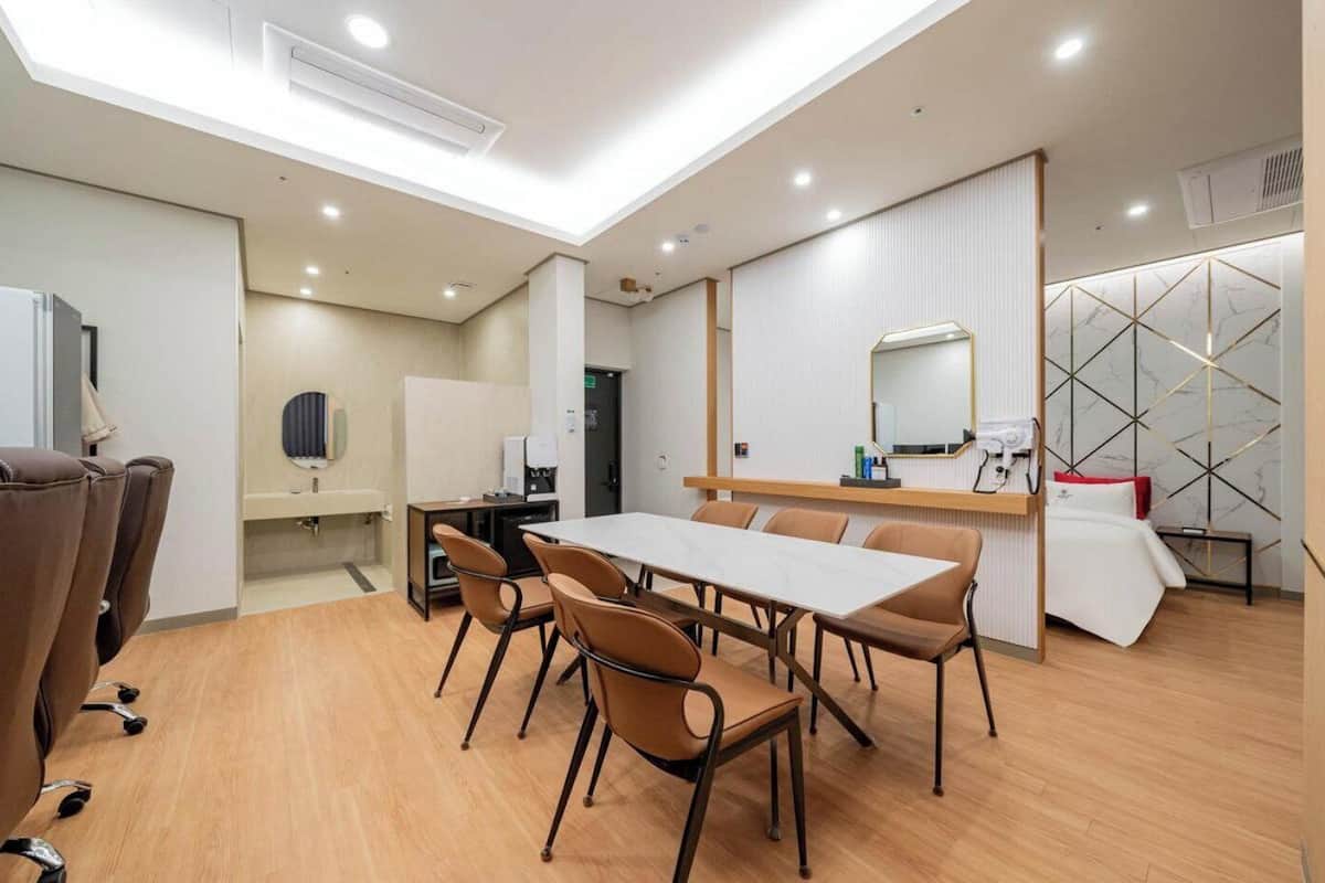 Une chambre d’hôtel moderne dotée d’un coin repas, d’une petite kitchenette et d’un lit agrémenté d’un mur décoratif.