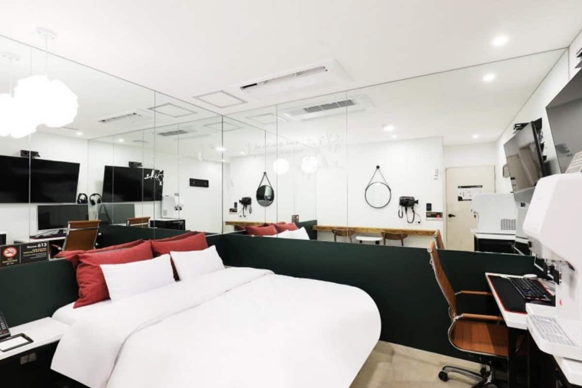Une chambre d’hôtel moderne avec un grand lit, un bureau équipé d’un ordinateur, une chaise et une petite table.