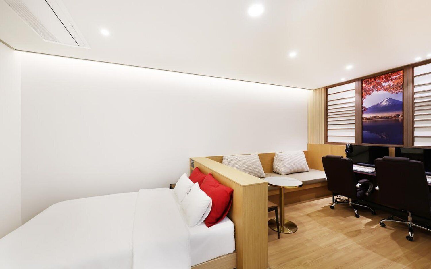 A modern hotel room with a bed, a desk, and a computer setup.
