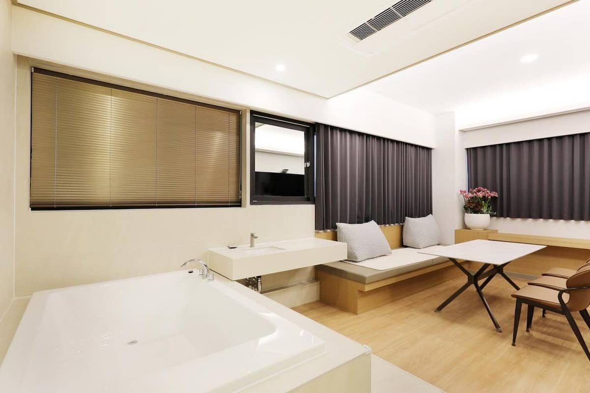 A modern bathroom with a bathtub, a vanity with a mirror, and a seating area with a table and chairs.