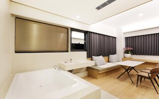 Un baño moderno con bañera, tocador con espejo y una zona de estar con mesa y sillas.