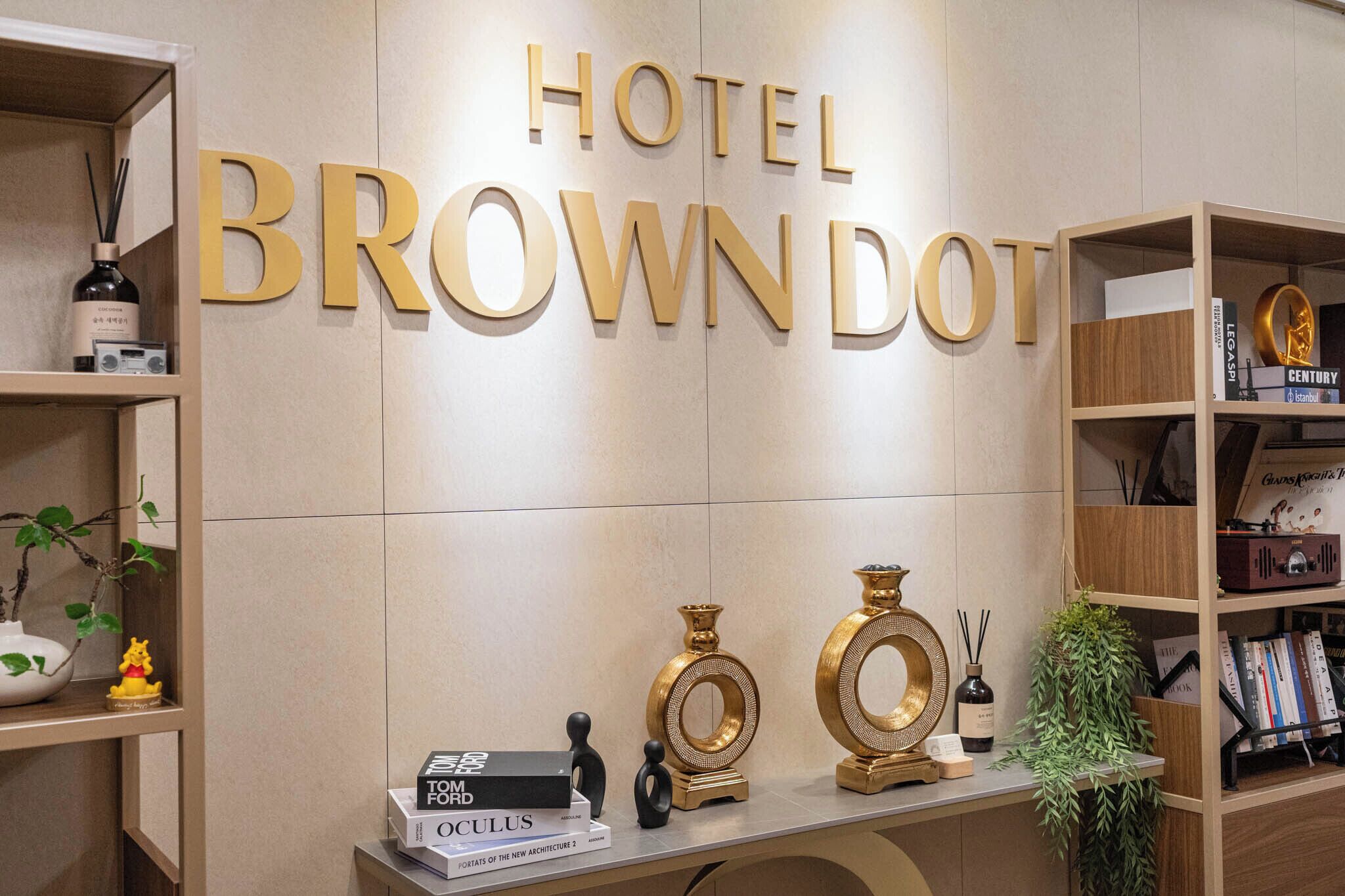A hotel sign with the name 'HOTEL BROWN DOT' and a shelf with books and decorative items.
