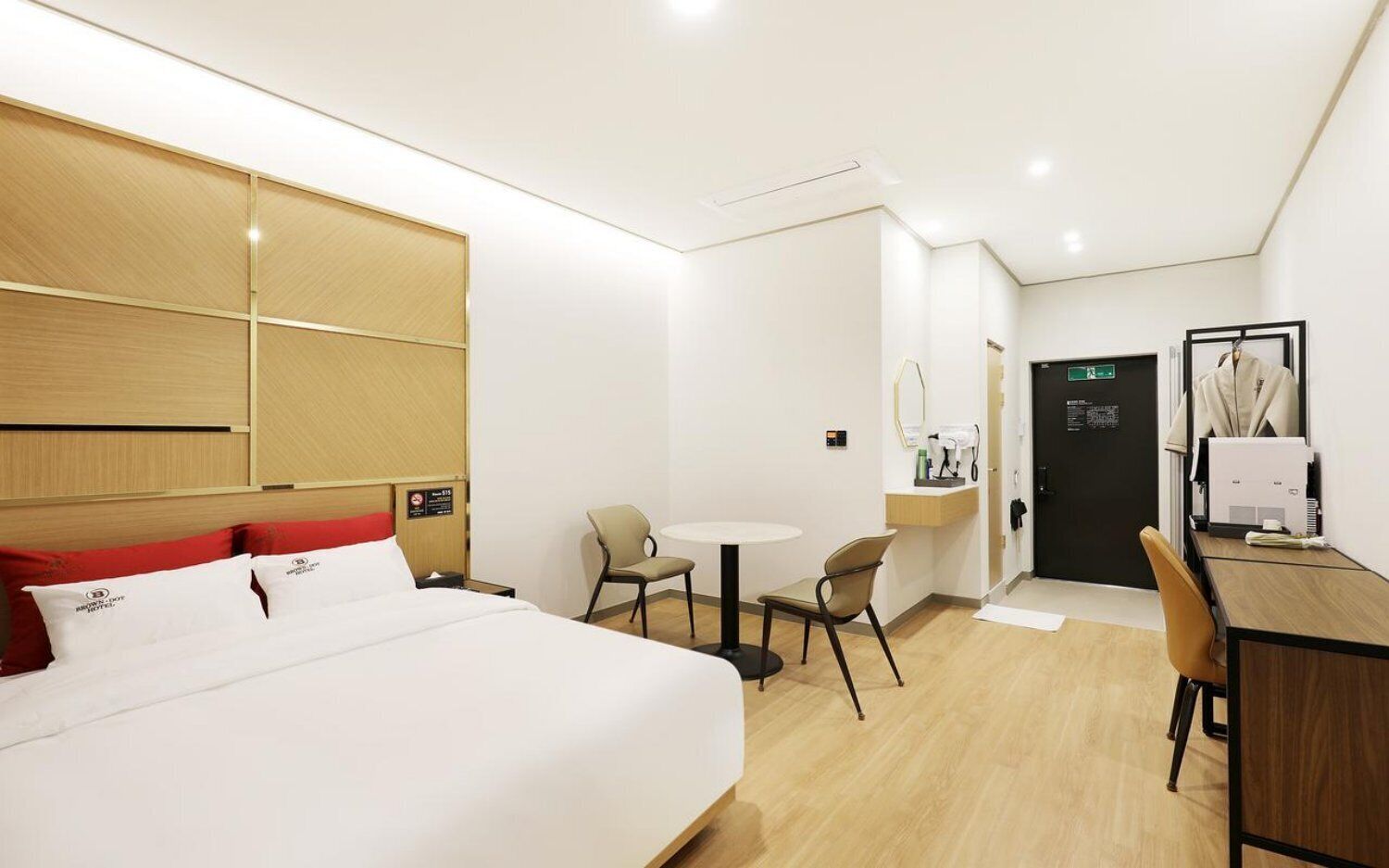 A hotel room with a bed, a desk, a chair, a small table, and a mirror.