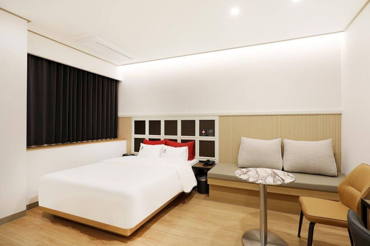 Une chambre d’hôtel avec un lit, une table de chevet, une chaise et une petite table avec une lampe.
