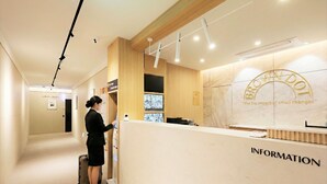 A reception area with a reception desk labeled 'INFORMATION,' a wooden panel wall, and a ceiling with recessed lighting. - Hotel Brown Dot (Dongducheon Central Station) (Dongducheon)