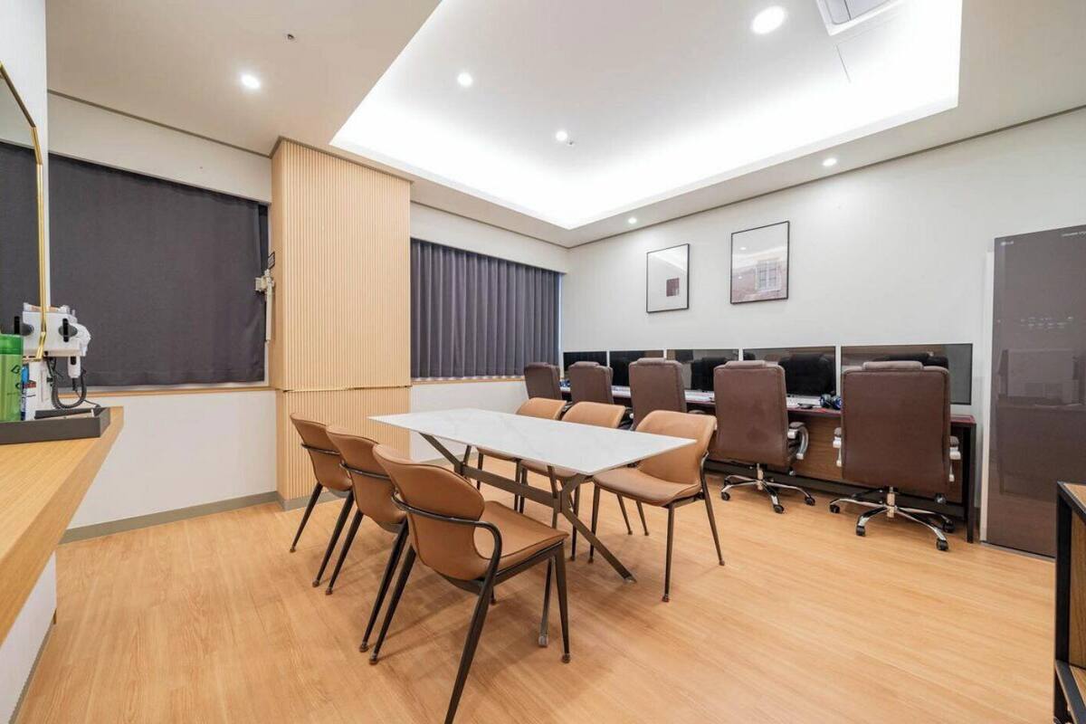 Une salle de conférence moderne, dotée d’une longue table, de nombreuses chaises et d’une rangée d’ordinateurs.