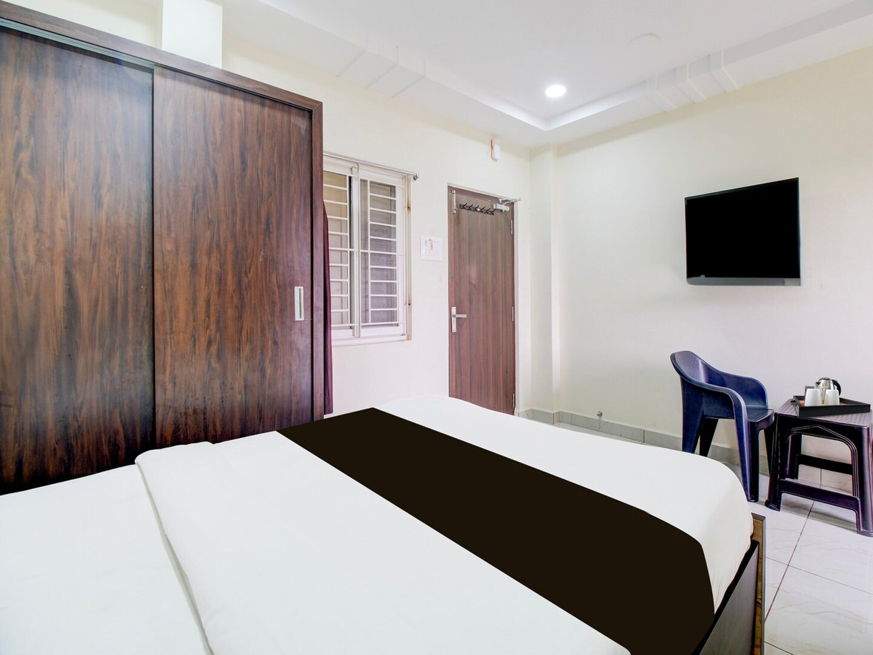 A hotel room with a bed, wardrobe, TV, and a small table with chairs.