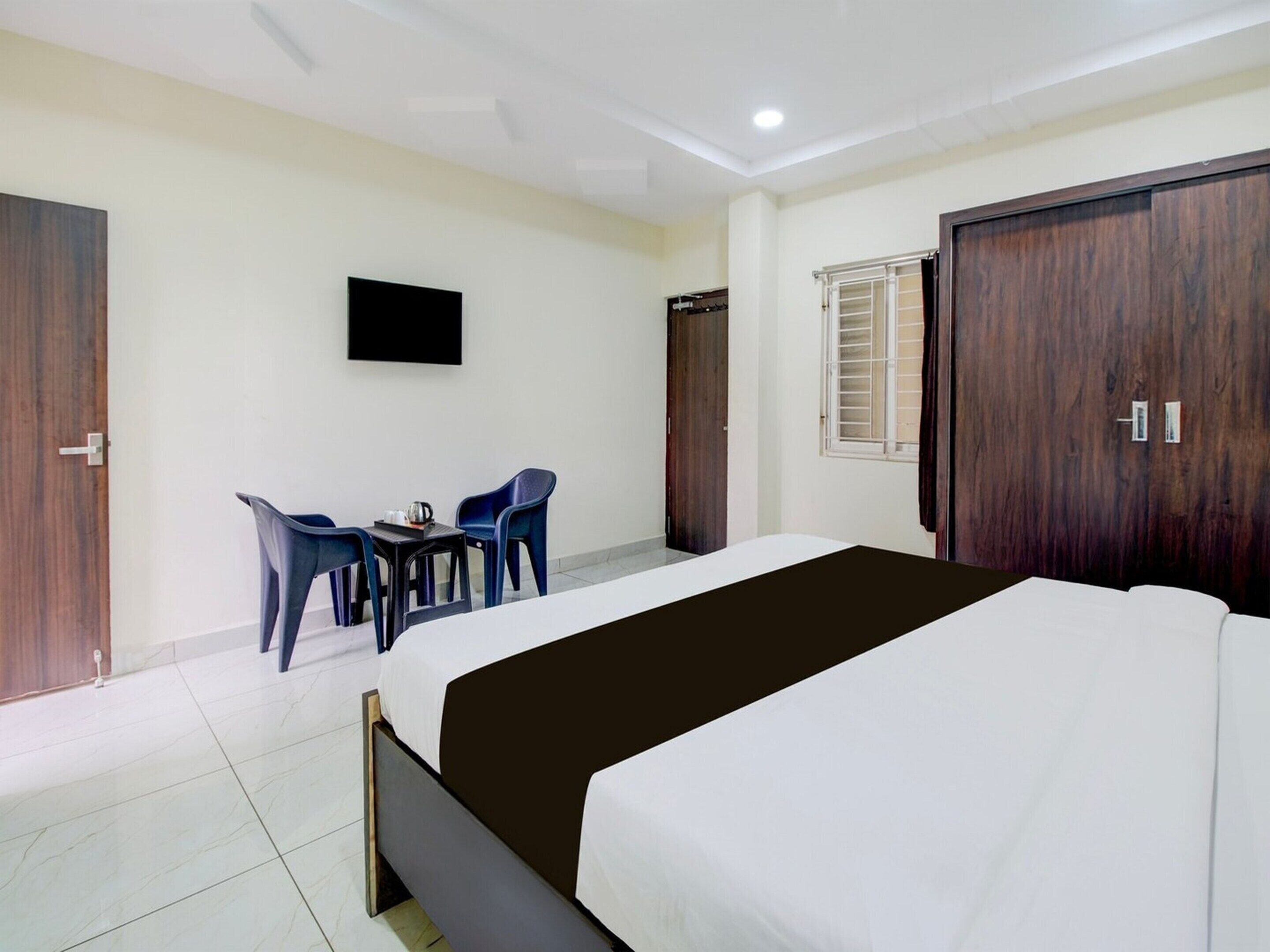Une chambre d’hôtel équipée d’un lit, d’un téléviseur fixé au mur, d’un bureau avec des chaises et d’une armoire.