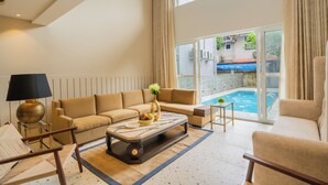 Una sala de estar moderna con sofá, mesa de centro, lámpara y vista a una piscina.