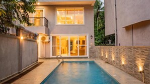 Una casa moderna de dos pisos con piscina, balcón y entrada bien iluminada.