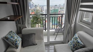 Un soggiorno moderno con un divano, una poltrona e un balcone che si affaccia sulla città.